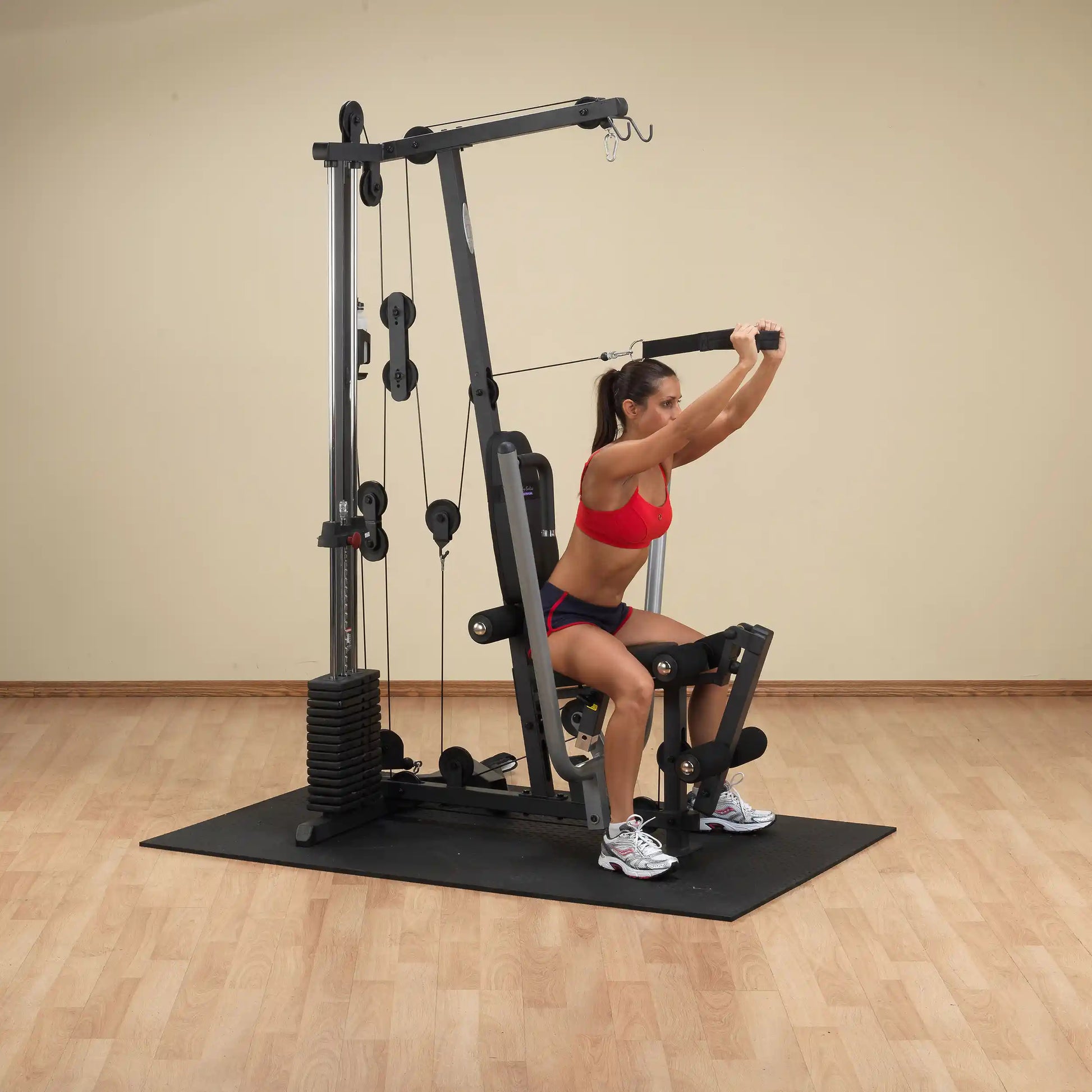Woman using a home gym machine in red sportswear for strength training.