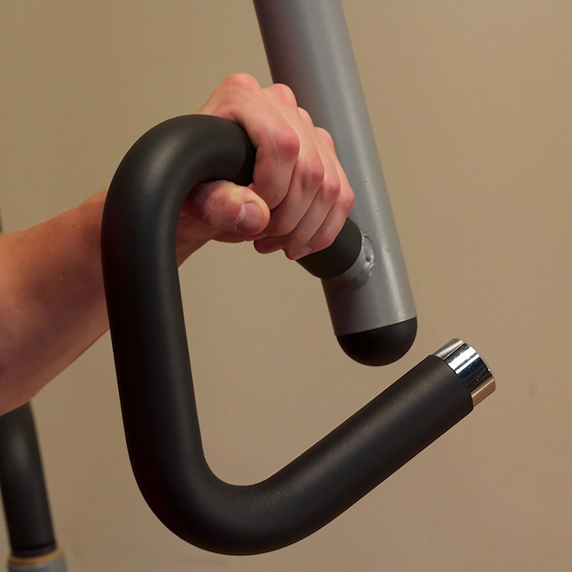 Hand gripping a black ergonomic handle on a gym machine for strength training.