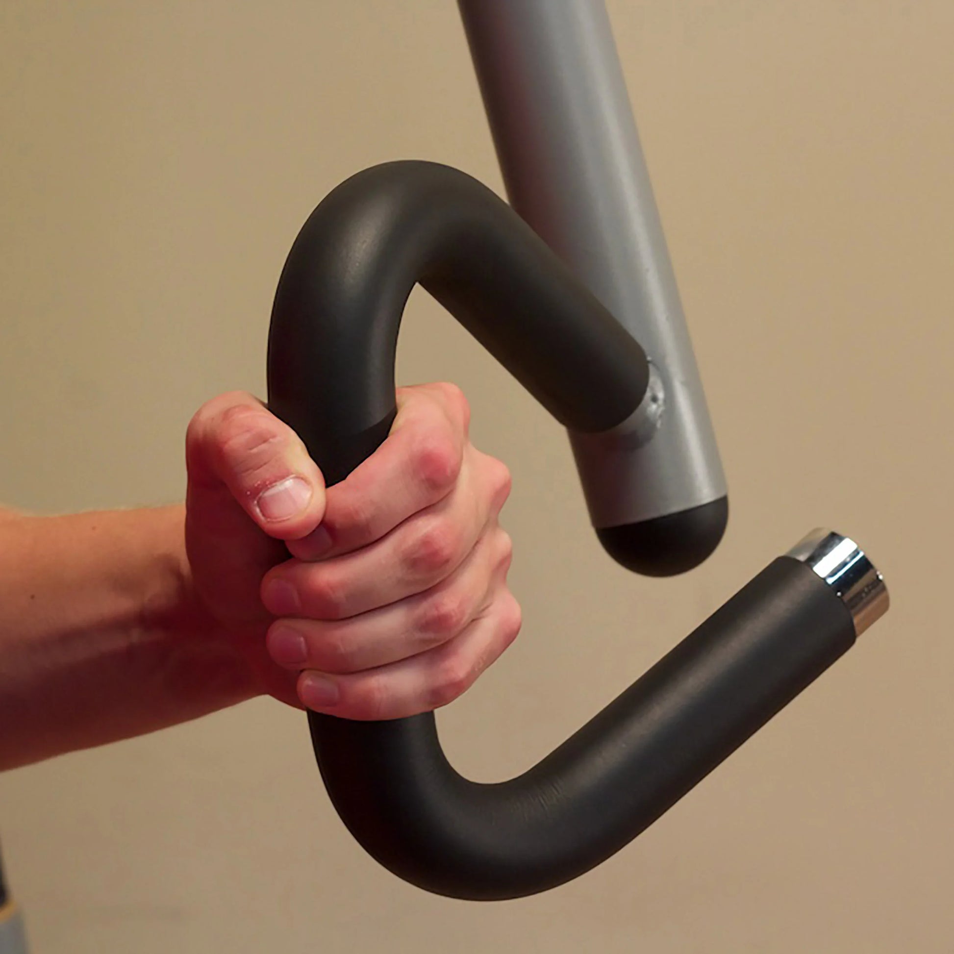Hand gripping black ergonomic exercise machine handle.