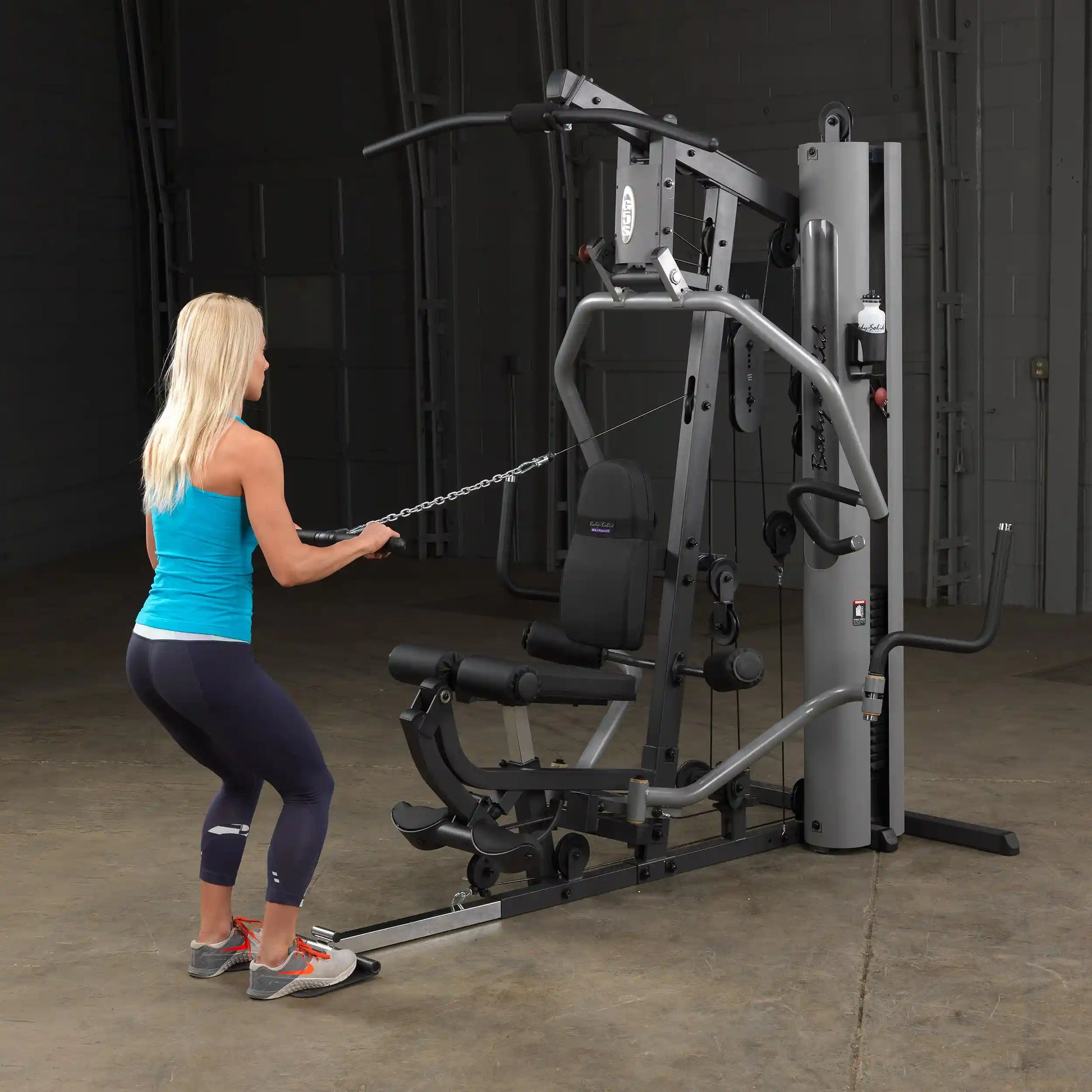 Woman using a Bowflex home gym with a black seat for strength training.