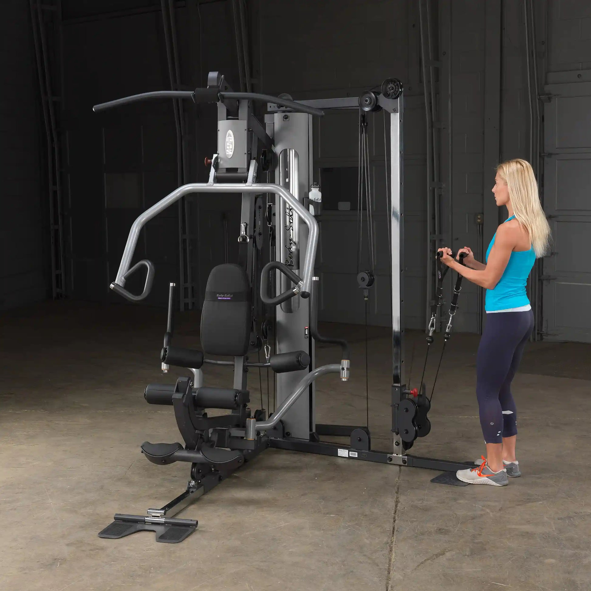 Woman using a Body-Solid home gym machine in a workout room.