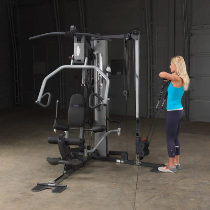 Woman using Body-Solid G6BR home gym with cable machine in a garage.