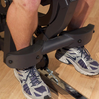 Man using a leg extension machine with Nike sneakers in a gym setting.