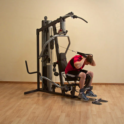 Man using multi-gym machine for strength training in a home gym setting.