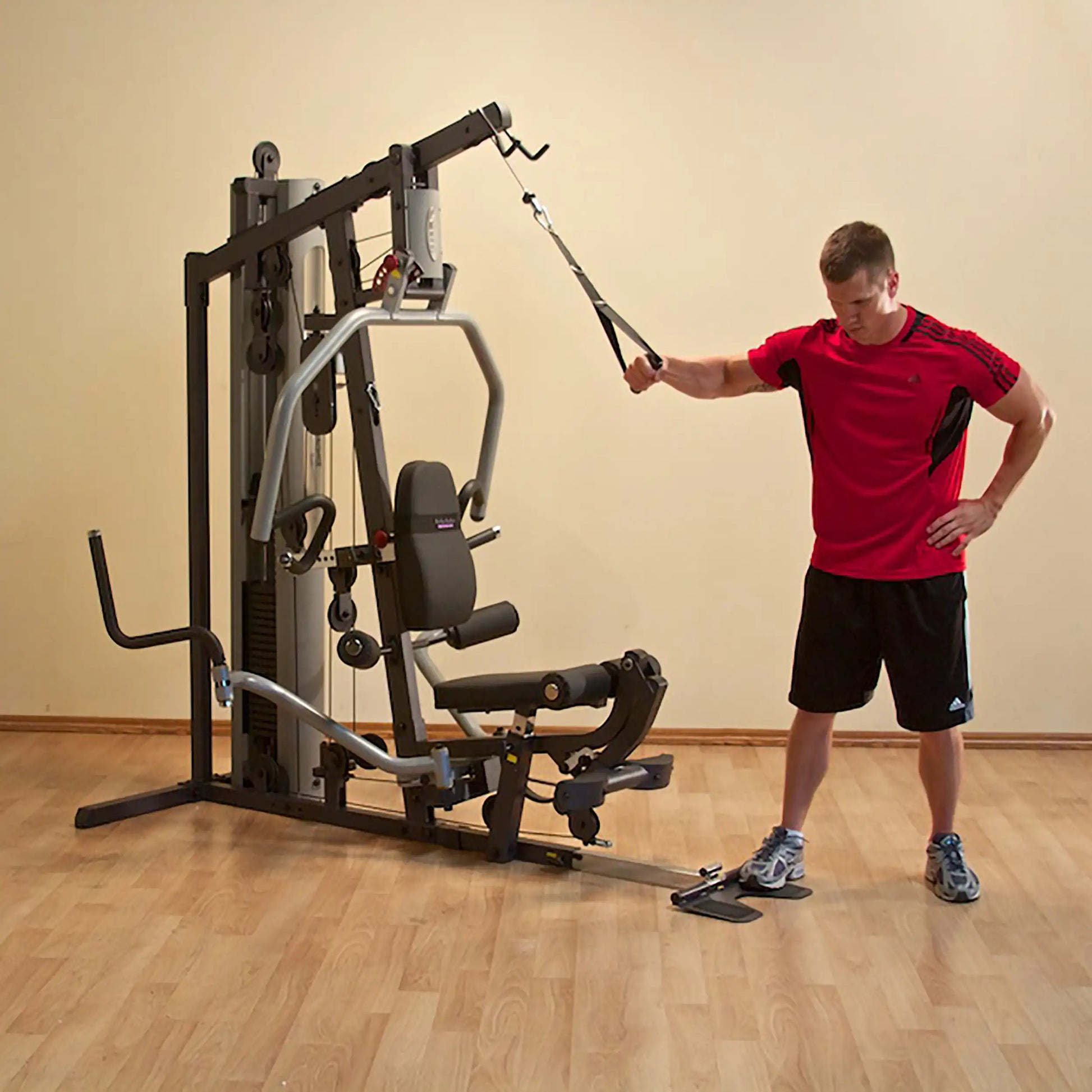 Man using a multi-station home gym in red shirt for strength training.