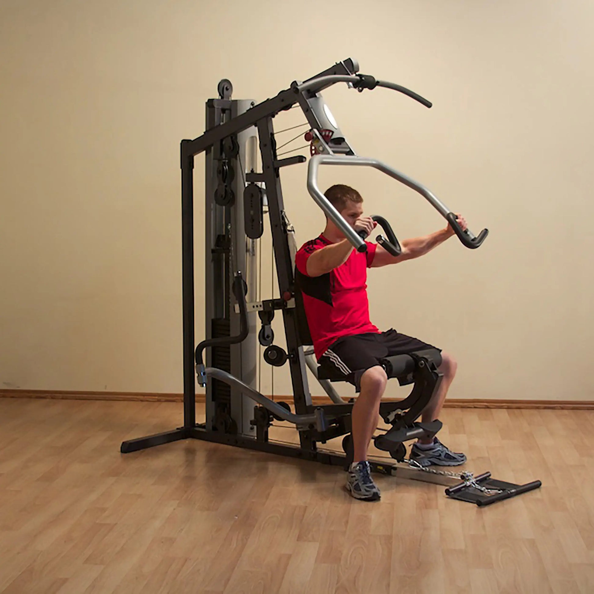 Man using multifunctional home gym machine in red shirt.