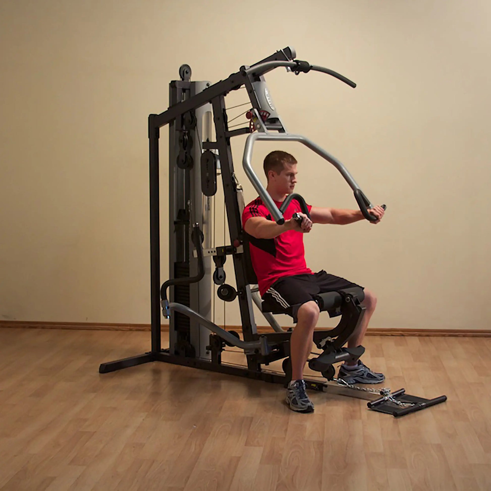 Man in red shirt using a home gym machine with a seated chest press.