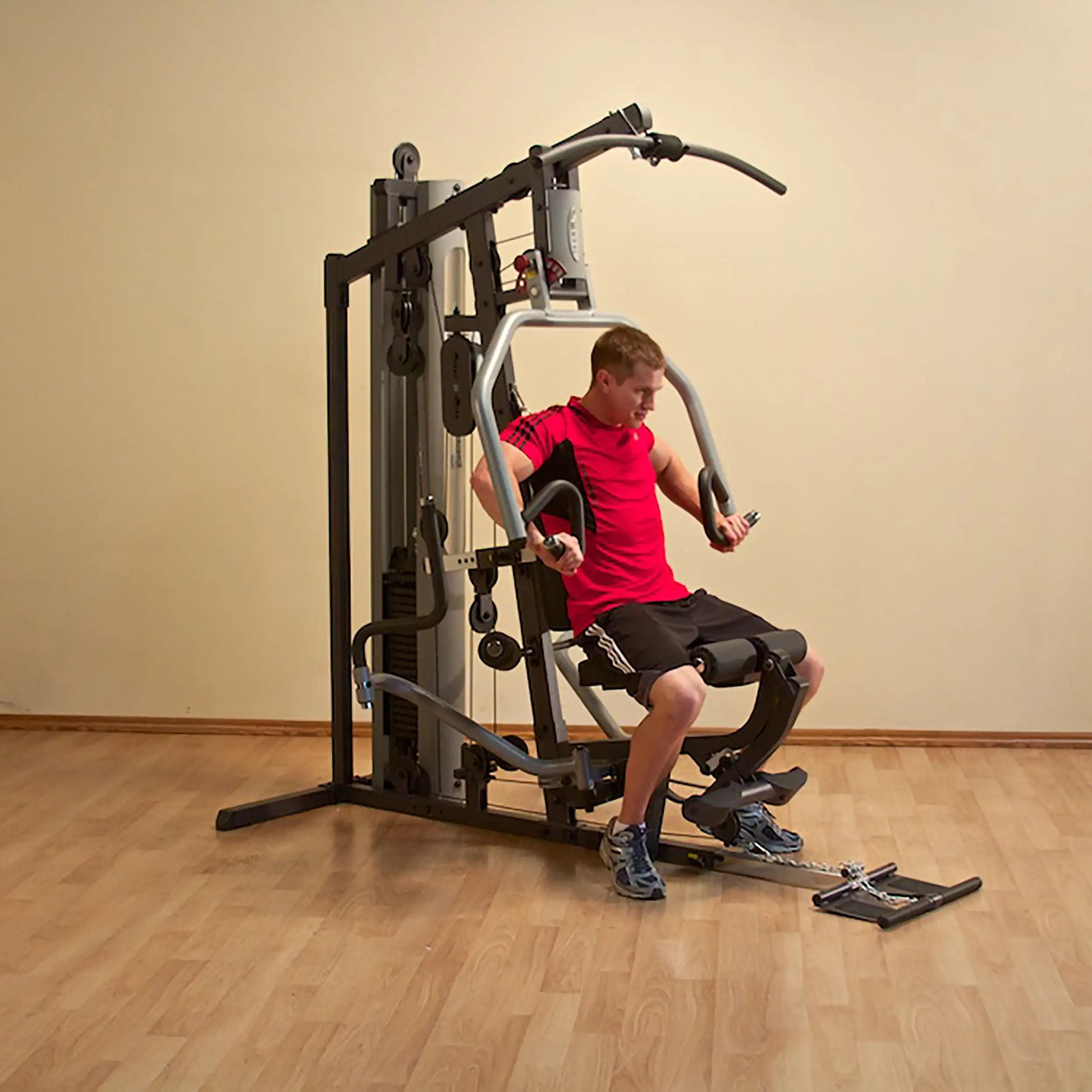 Man using a home gym machine for strength training in a red shirt.