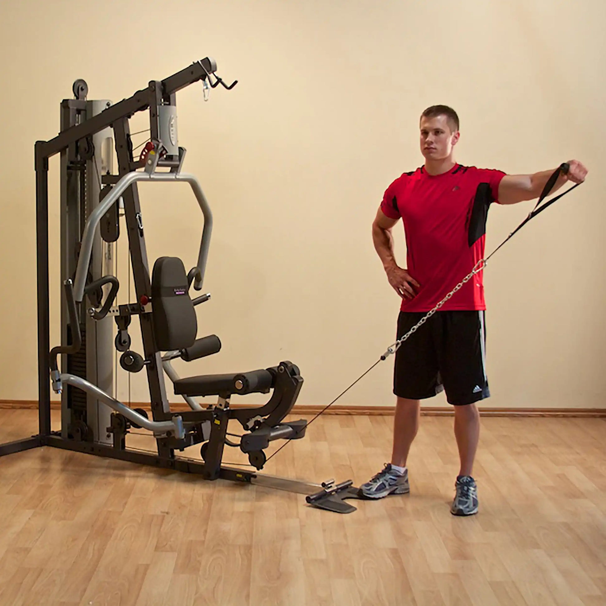 Man using a multi-gym machine for cable workout in red shirt.