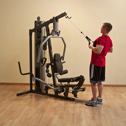 Man using home gym equipment in a red shirt, performing cable rows.