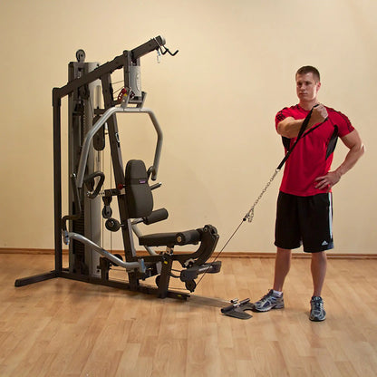 Man using a home gym cable machine for shoulder exercises in a red shirt.