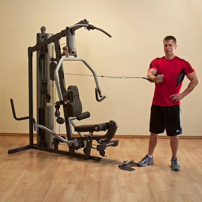 Man exercising with a home gym cable machine wearing a red shirt.