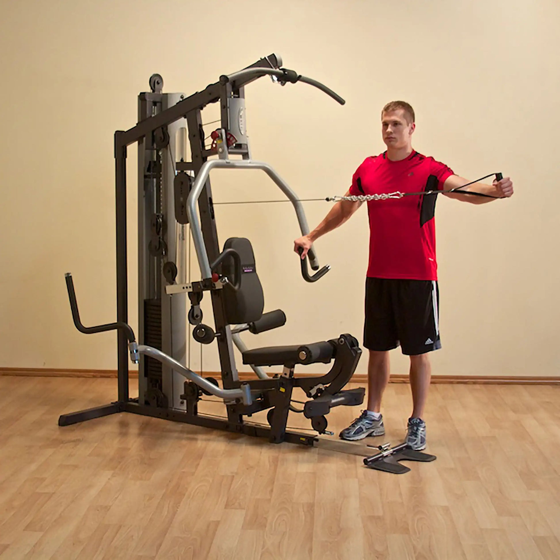 Man using multi-gym machine in red shirt for strength training.