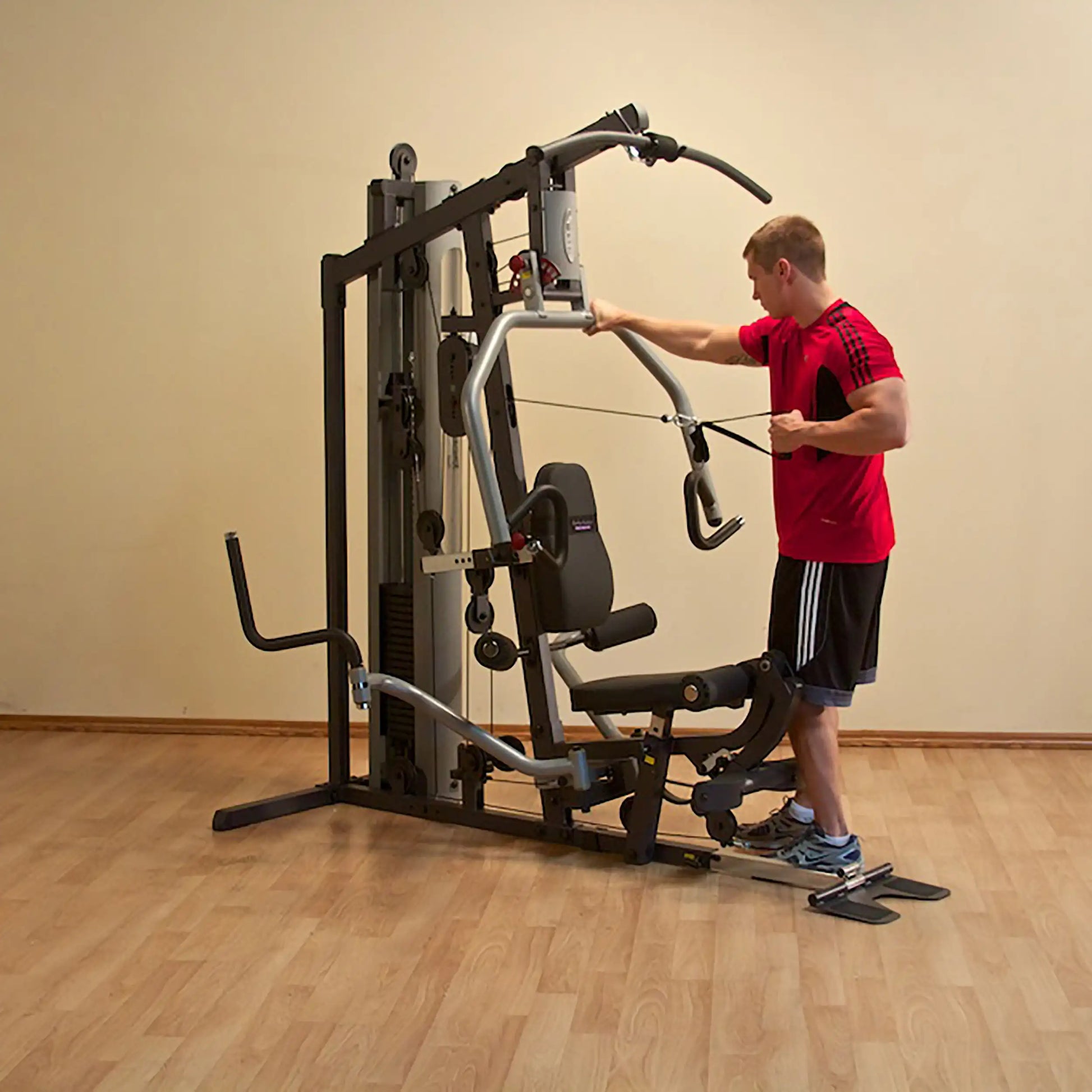 Man using a home gym machine in a red shirt, demonstrating strength training exercises.
