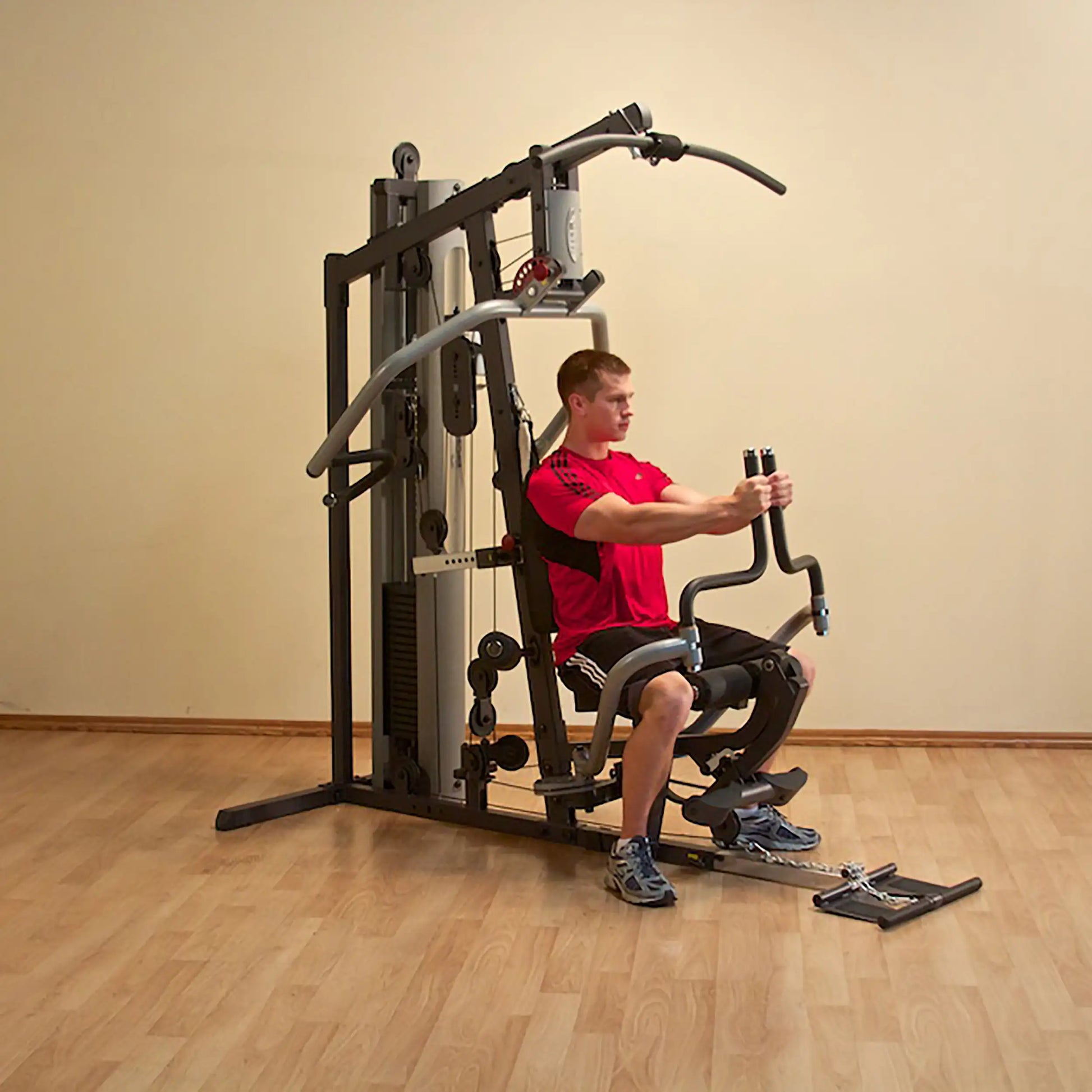 Man using a multifunctional home gym machine in a red shirt.
