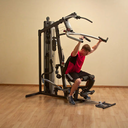 Man using a multi-station home gym in red shirt for strength training.