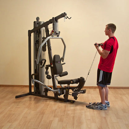 Man using home gym machine for cable curls in a red shirt.