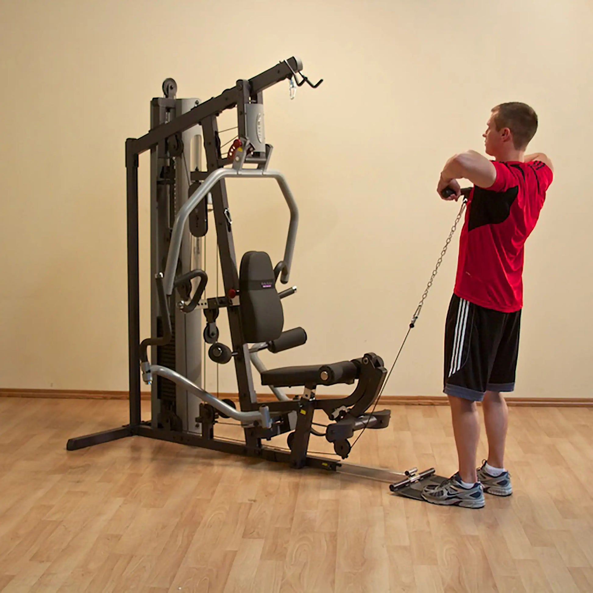 Man using a home gym machine for cable exercises in a red shirt.