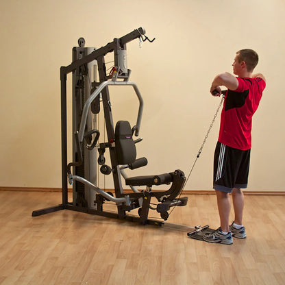 Man using a home gym machine for cable exercises in a red shirt.