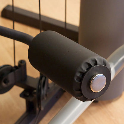 Black foam roller on gym equipment for leg exercises.