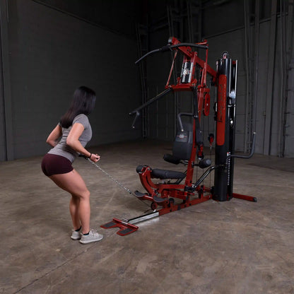 Woman using a red Bowflex home gym for strength training.