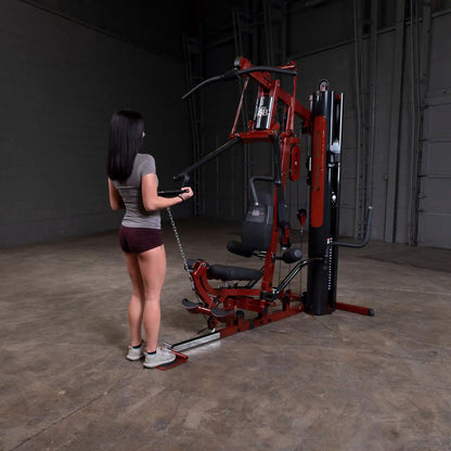 Woman using Body-Solid home gym with red frame in a spacious room.
