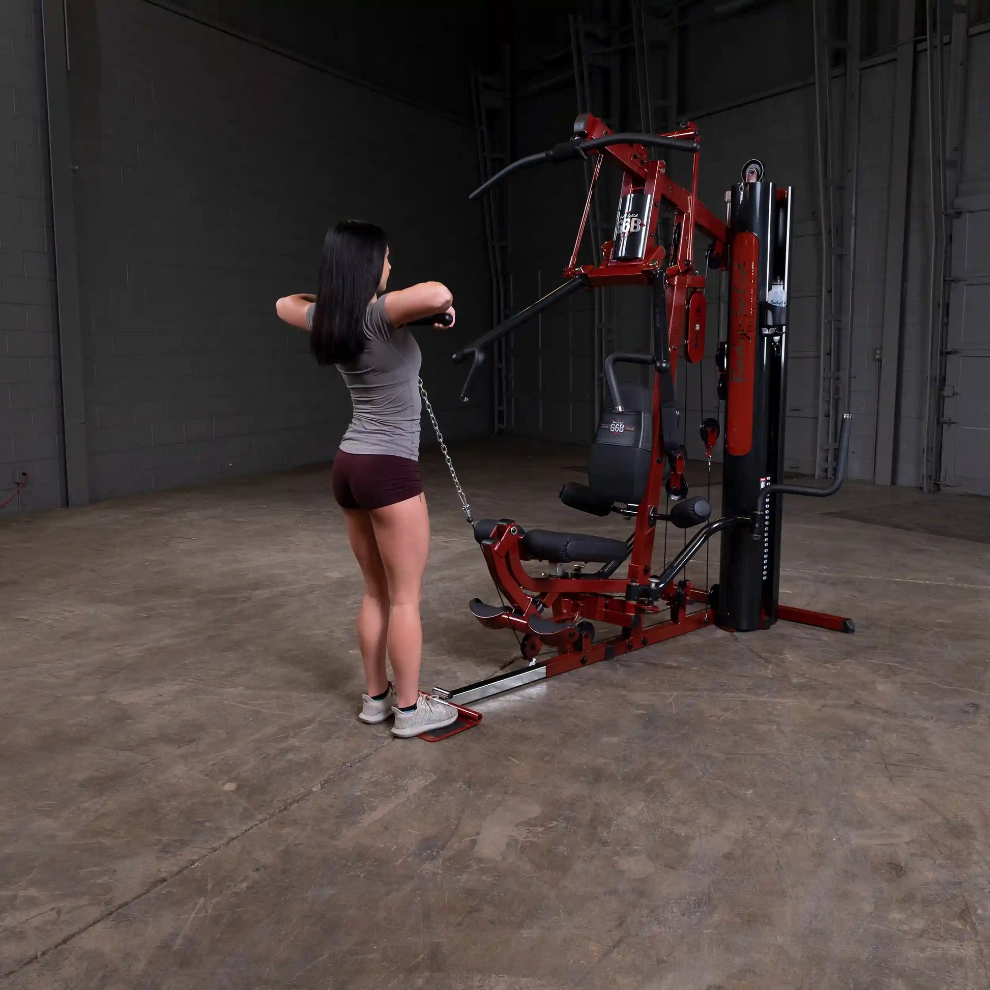 Woman using red home gym equipment for strength training workout.