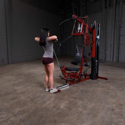 Woman using red home gym equipment for strength training workout.