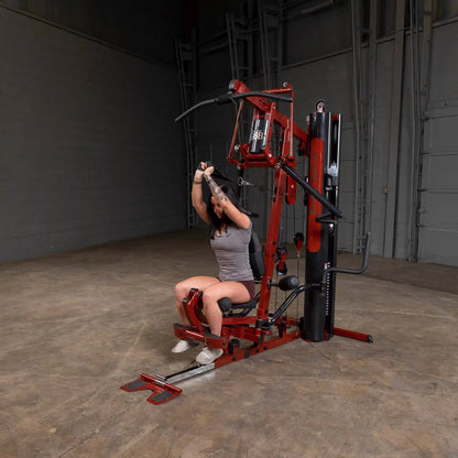 Woman using red Body-Solid home gym machine for strength training.