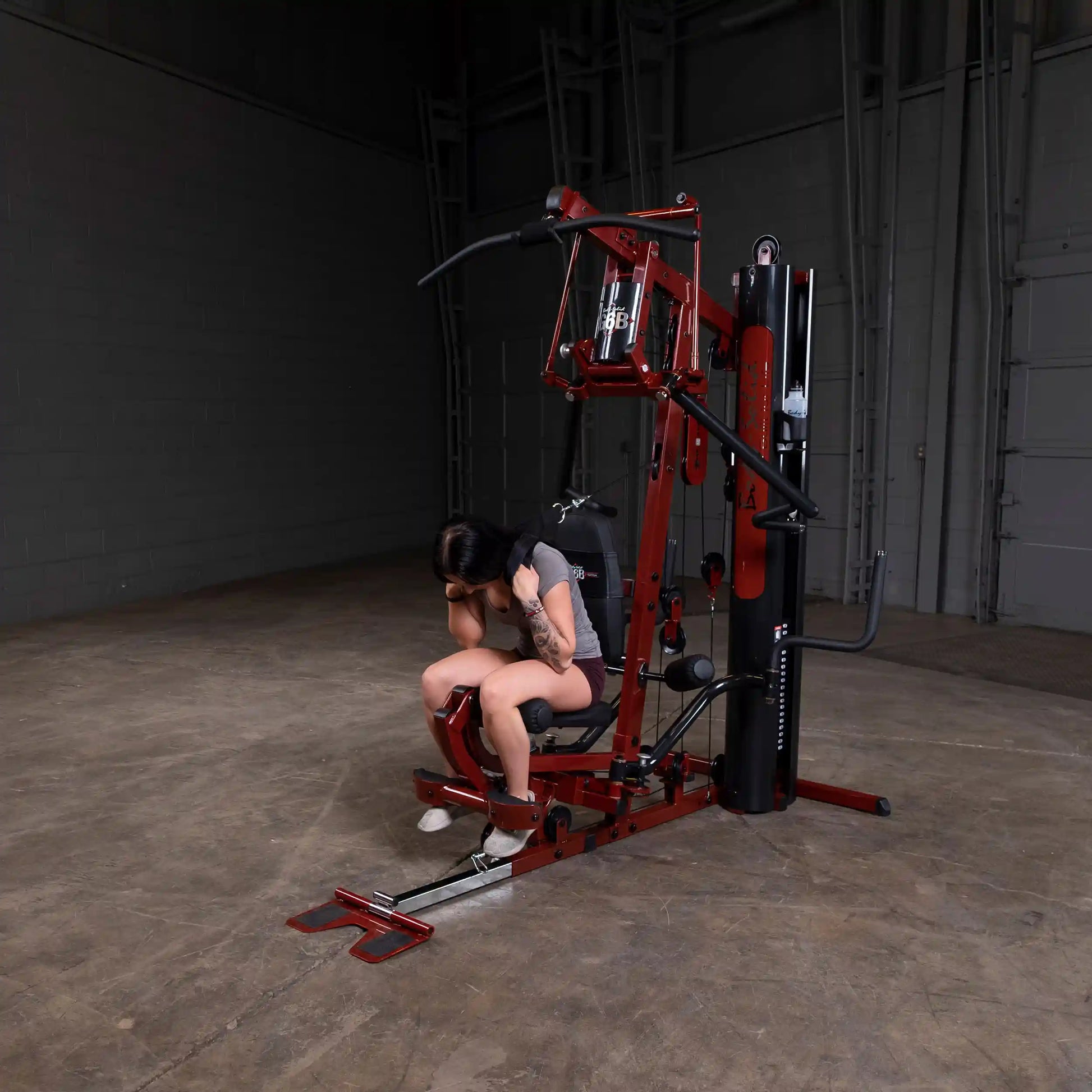 Woman using a red Body-Solid Smith machine for strength training in a gym.