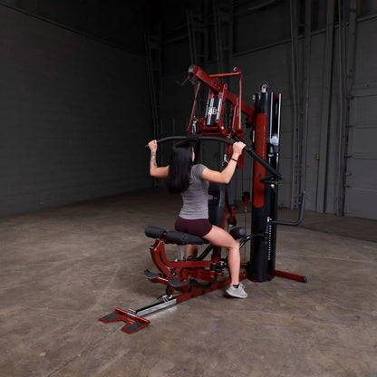 Woman using a red Body-Solid home gym machine for strength training.