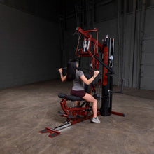 Woman using red Body-Solid home gym machine for strength training.