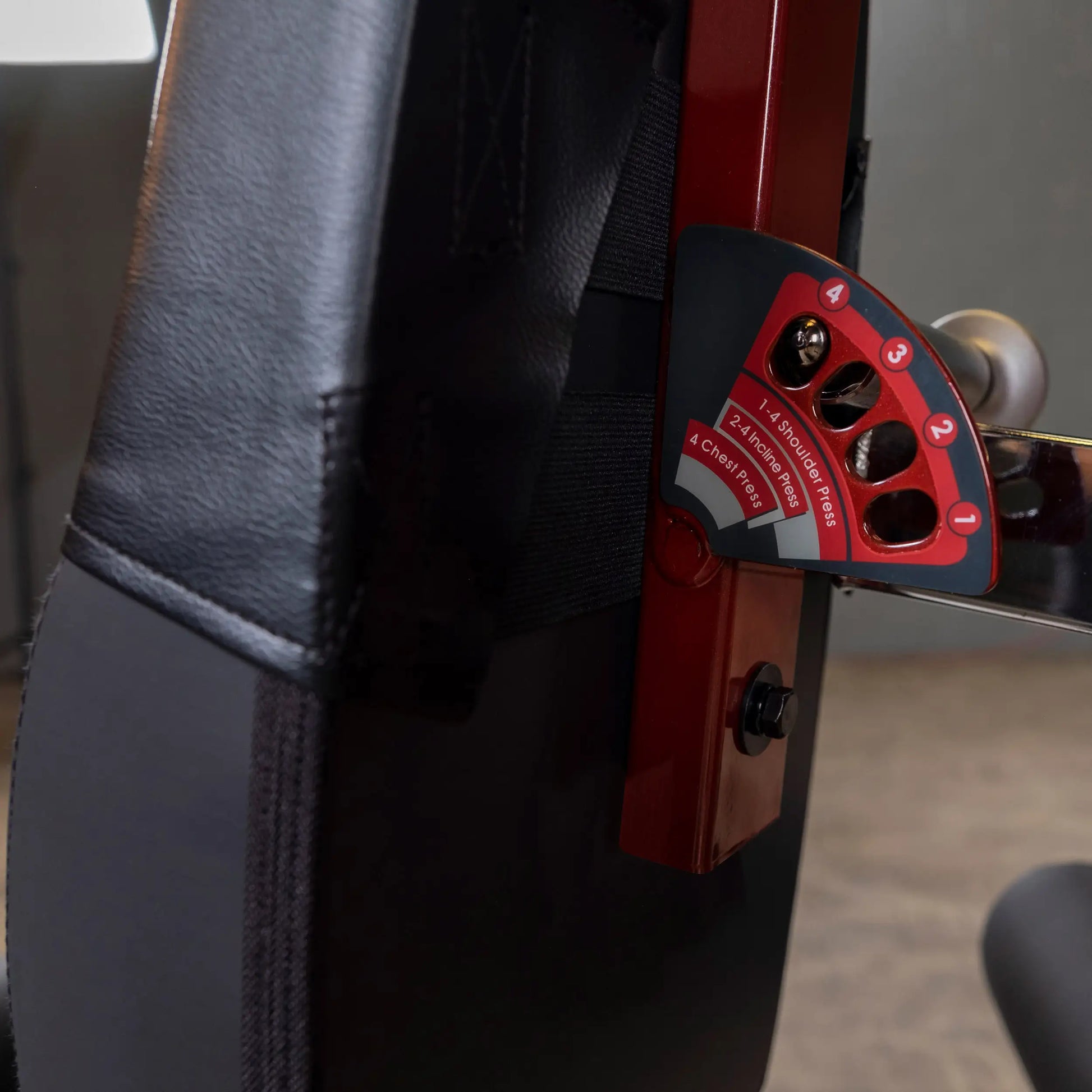 Adjustable weight bench with black padding and red angle selector for chest and shoulder press exercises.