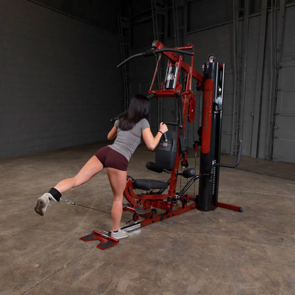 Woman using red Bowflex home gym for leg workout in industrial space.