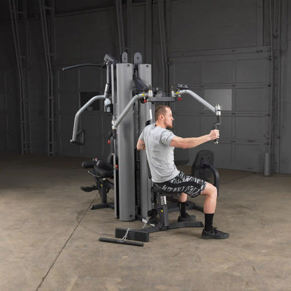 Man using Body-Solid home gym machine in a garage setting for strength training.