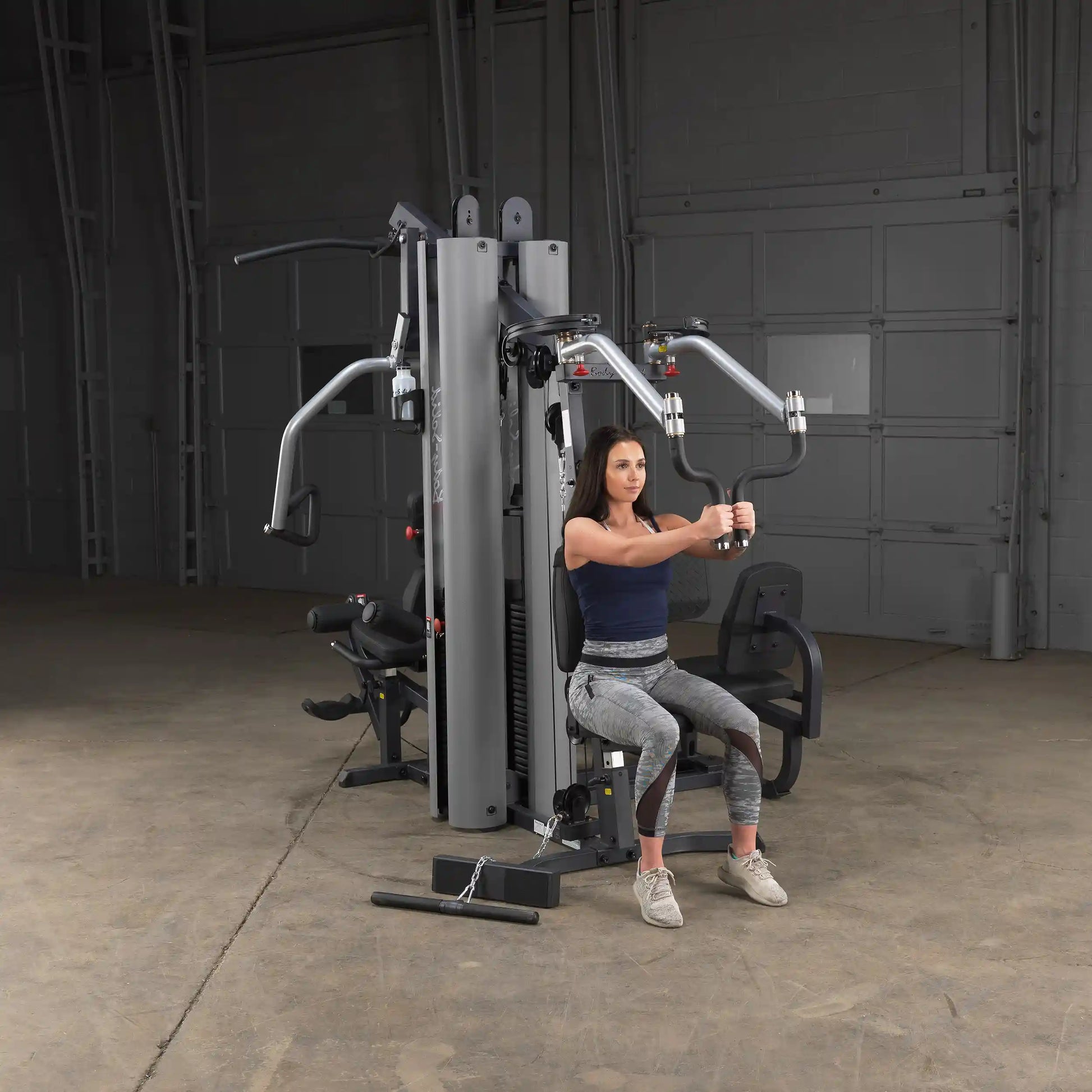 Woman using Body-Solid multi-station gym equipment in a spacious workout area.