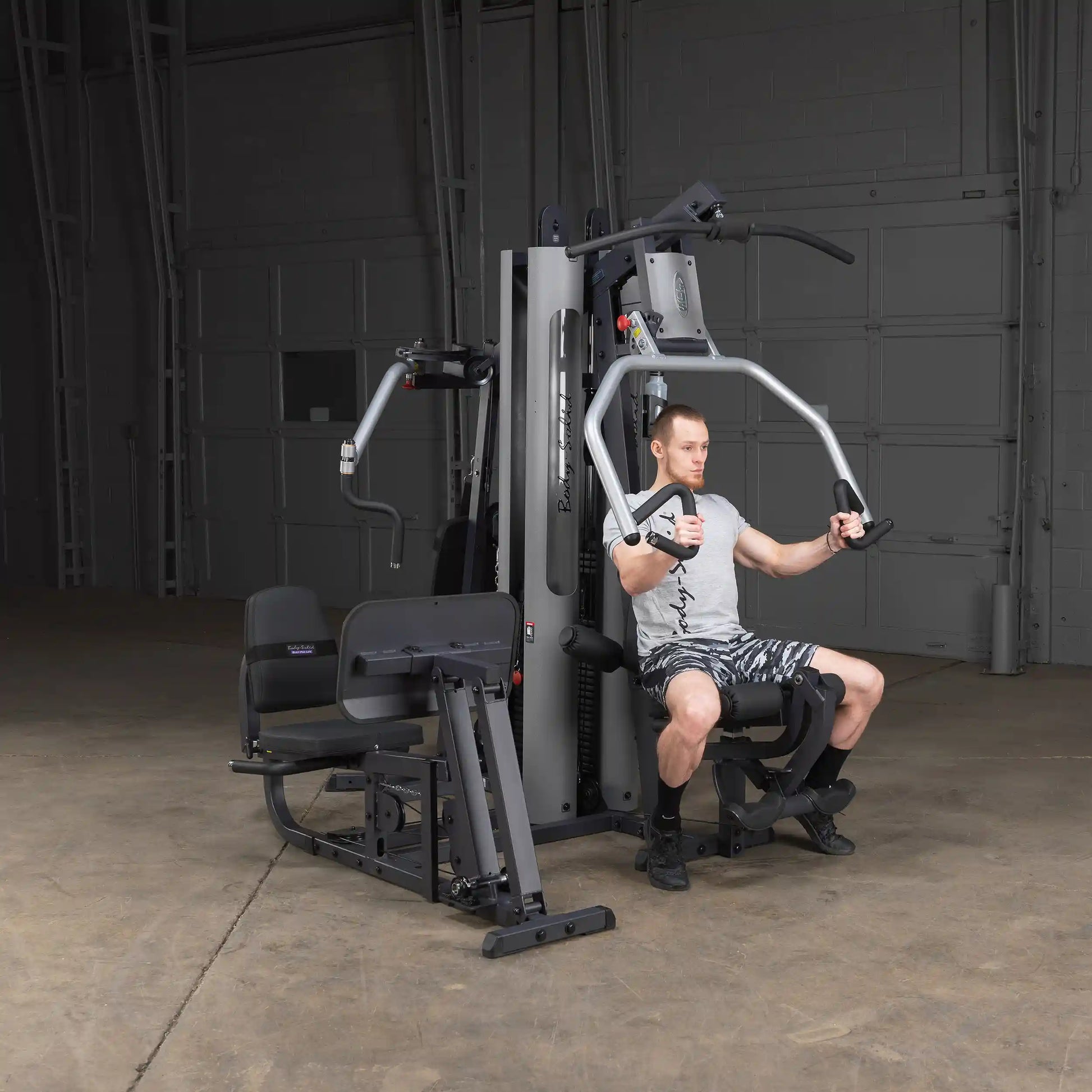 Man using Body-Solid home gym with chest press in a garage setting.