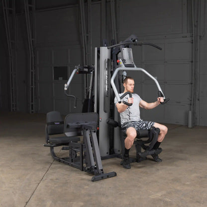 Man using Body-Solid home gym with chest press in a garage setting.