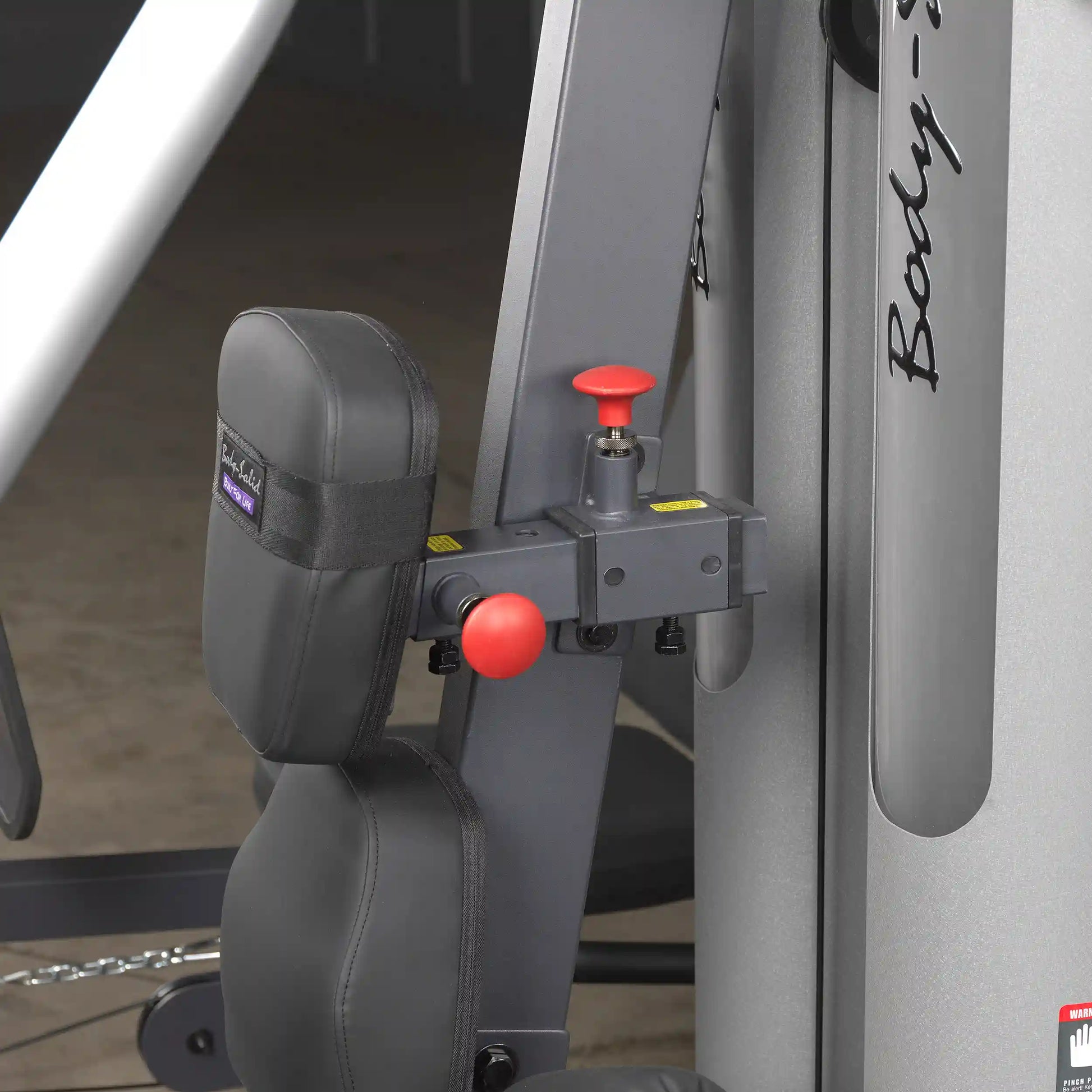 Body-Solid strength machine with black padded seat and red adjustment knob.