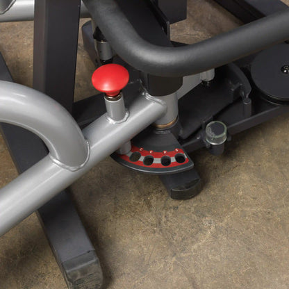 Gym equipment with adjustable settings and red pin on concrete floor.