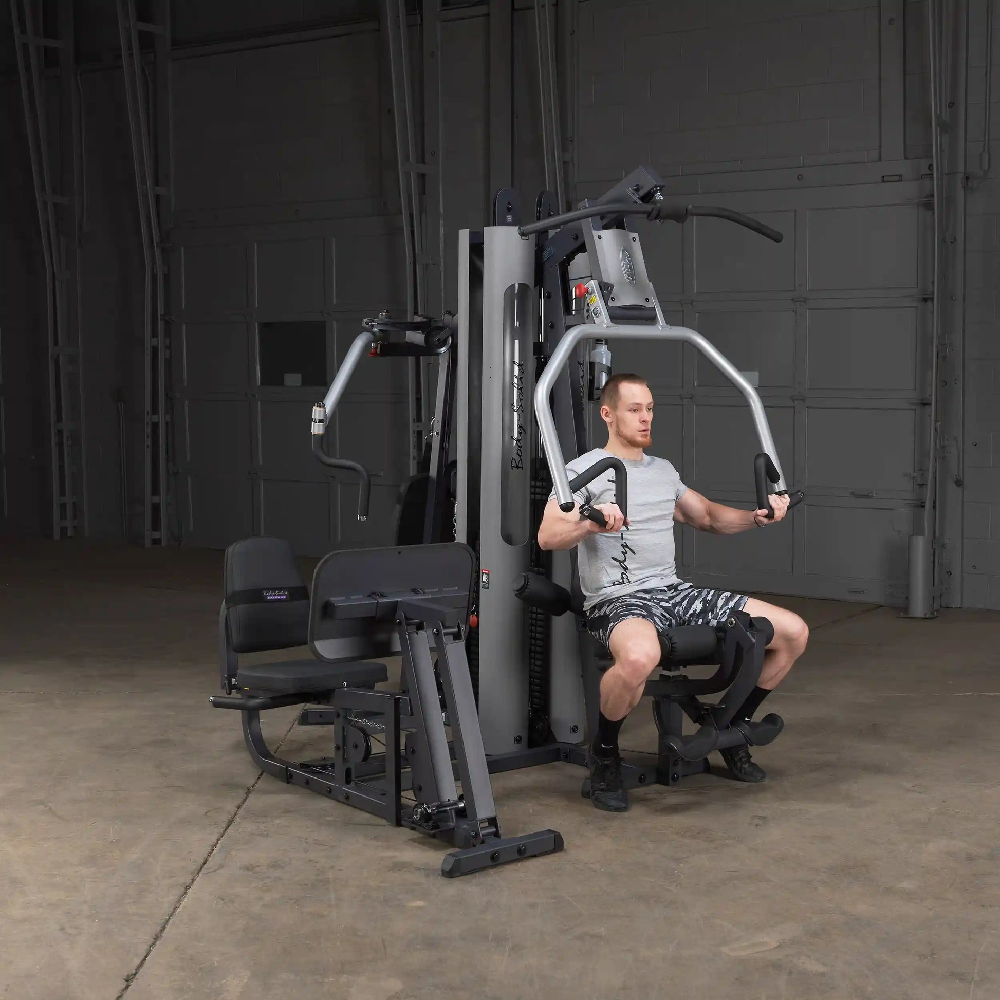 Man using Body-Solid home gym machine for chest press in a garage setting.