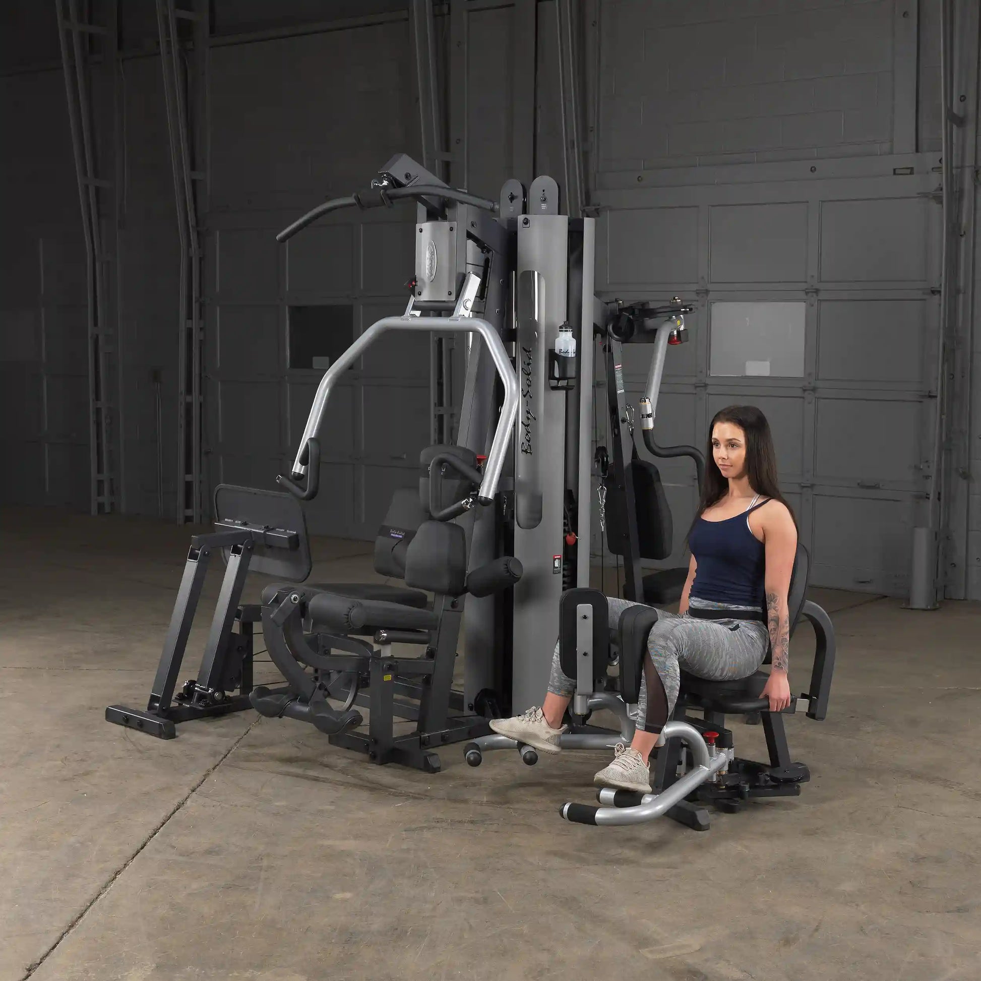 Woman using Body-Solid home gym with leg extension in a spacious room.