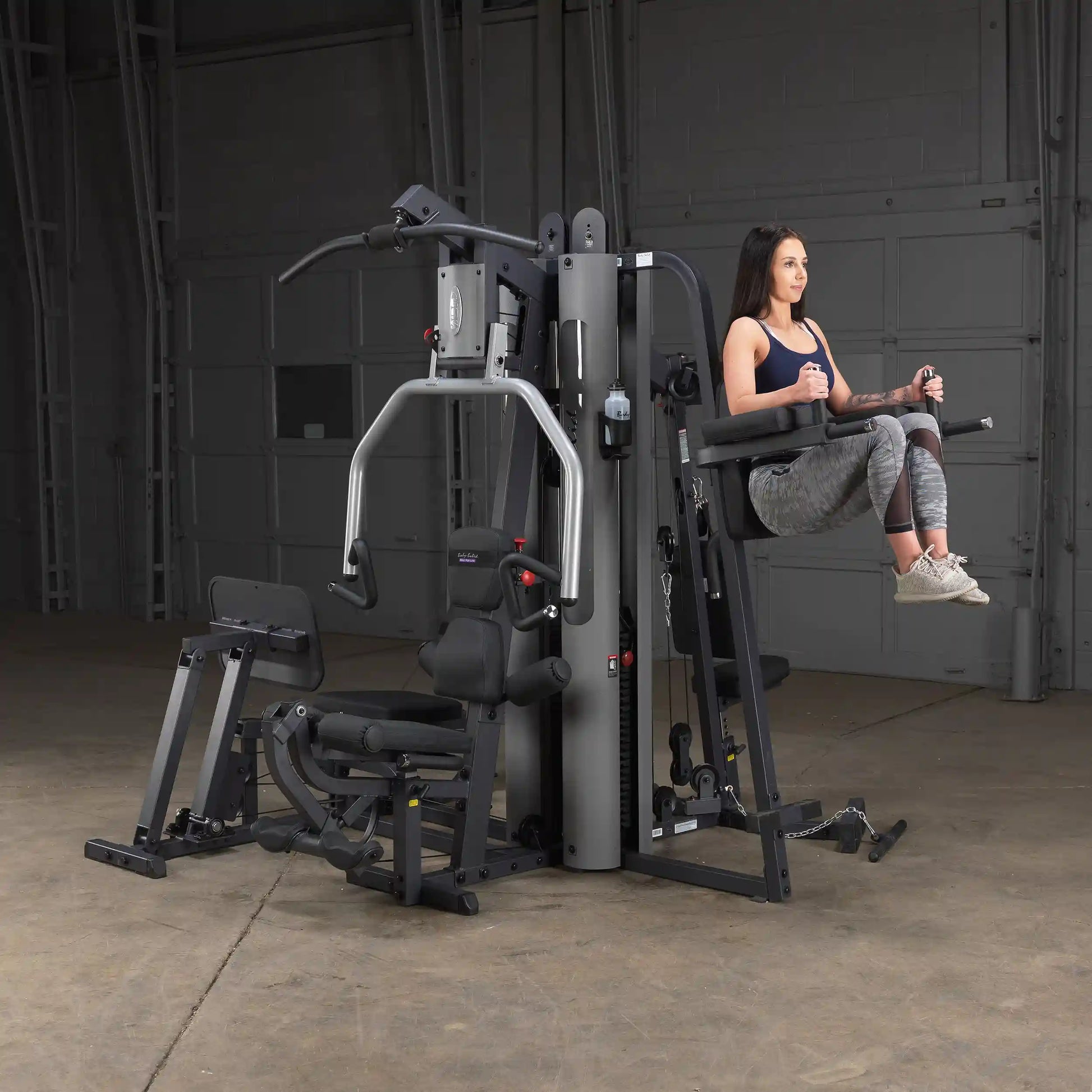 Woman using BodyCraft XPress Pro gym machine for leg raises.