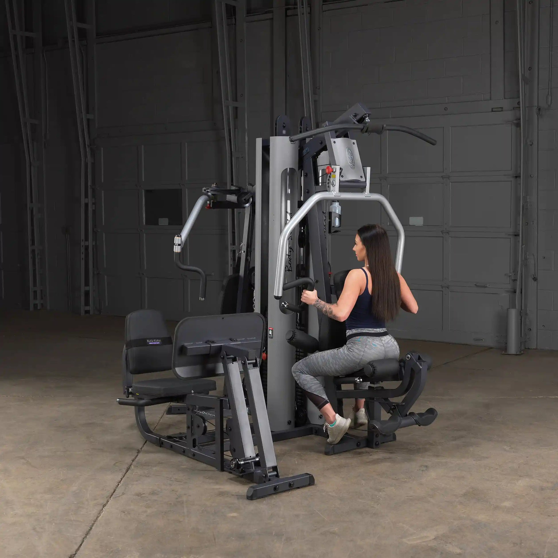 Woman using Inspire Fitness M3 Home Gym in a warehouse setting.