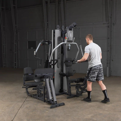 Man using Body-Solid home gym for strength training in a spacious warehouse setting.