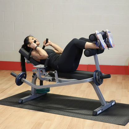 Woman using a leg press machine in a gym, wearing black workout outfit and white sneakers.