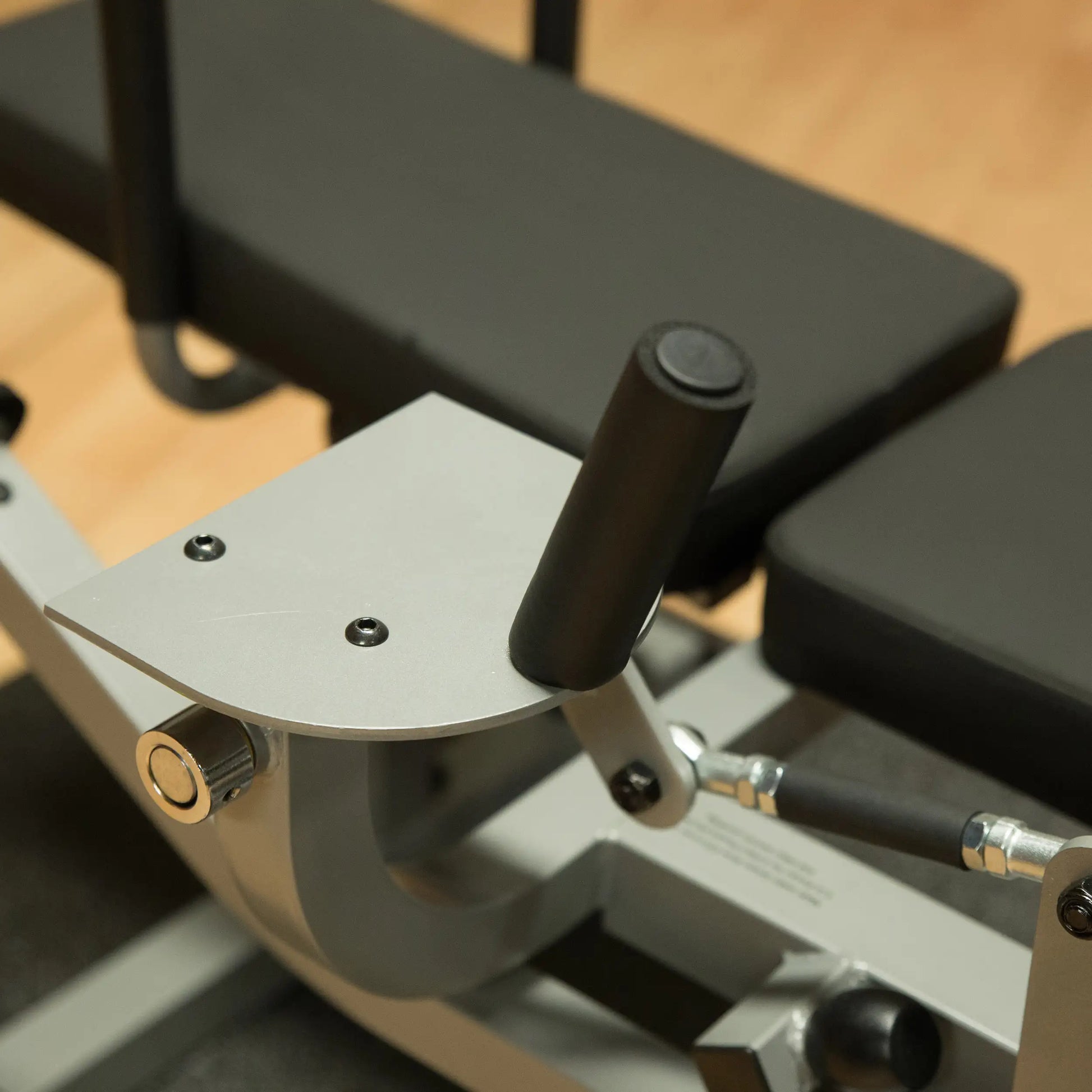 Gym equipment handlebar with black grips on a silver frame for rowing exercise.