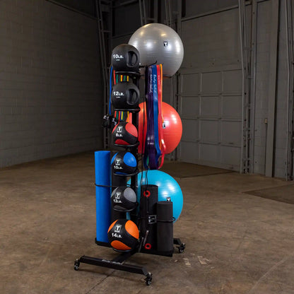 Body-Solid storage rack with exercise balls, kettlebells, resistance bands, and yoga mats in a gym setting.