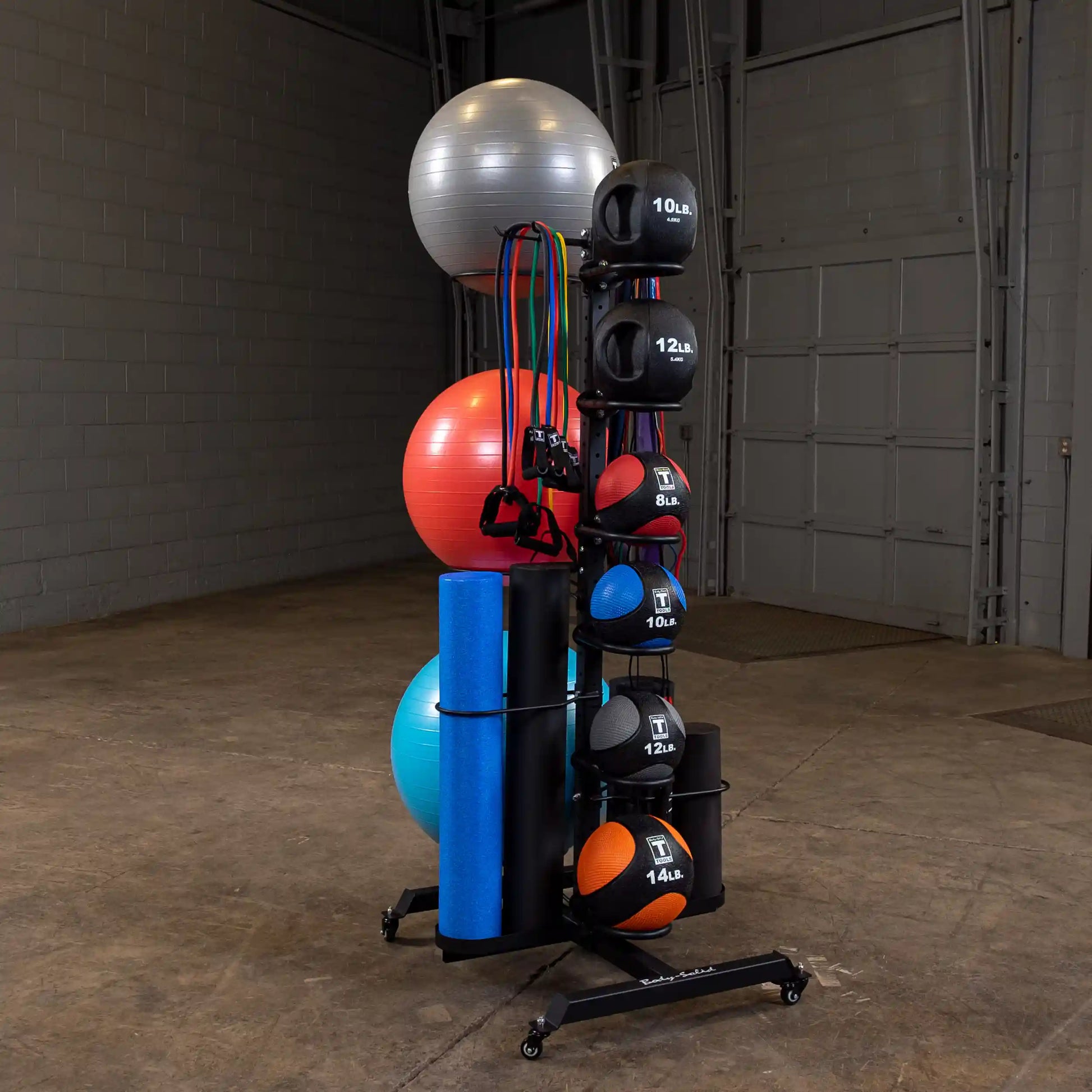 Exercise equipment rack with medicine balls, resistance bands, and yoga mats in a gym.