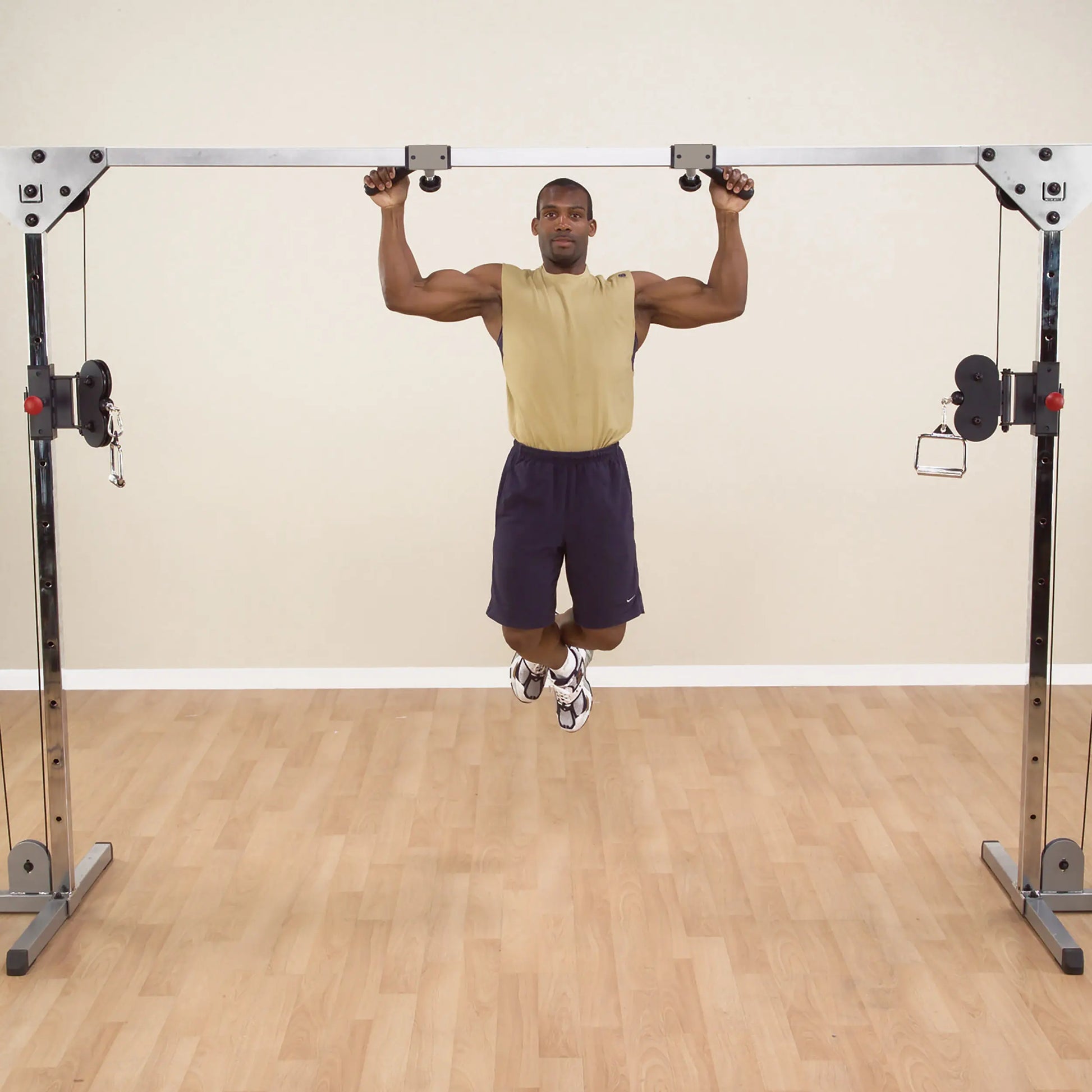 Man performing pull-up on cable crossover machine in gym.